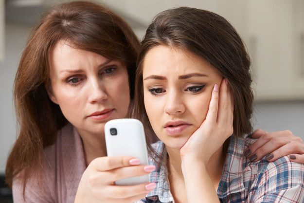 parent and child looking at device for signs your child is addicted to drugs