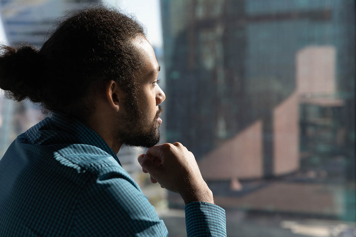 a man looking out a window thinking about medication-assisted treatment
