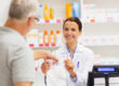 a pharmacist hands a prescription off to a customer after explaining the risks