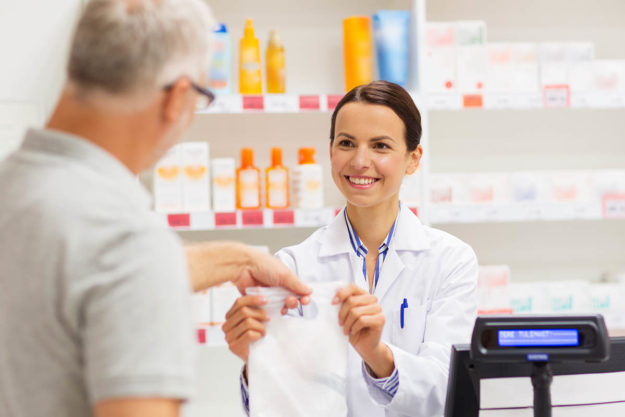 a pharmacist hands a prescription off to a customer after explaining the risks