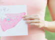 photo of a woman with a pink shirt holding a photo of a liver with a band aid indicating it needs to heal